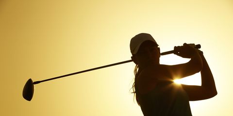 Silhouette of woman playing golf on course